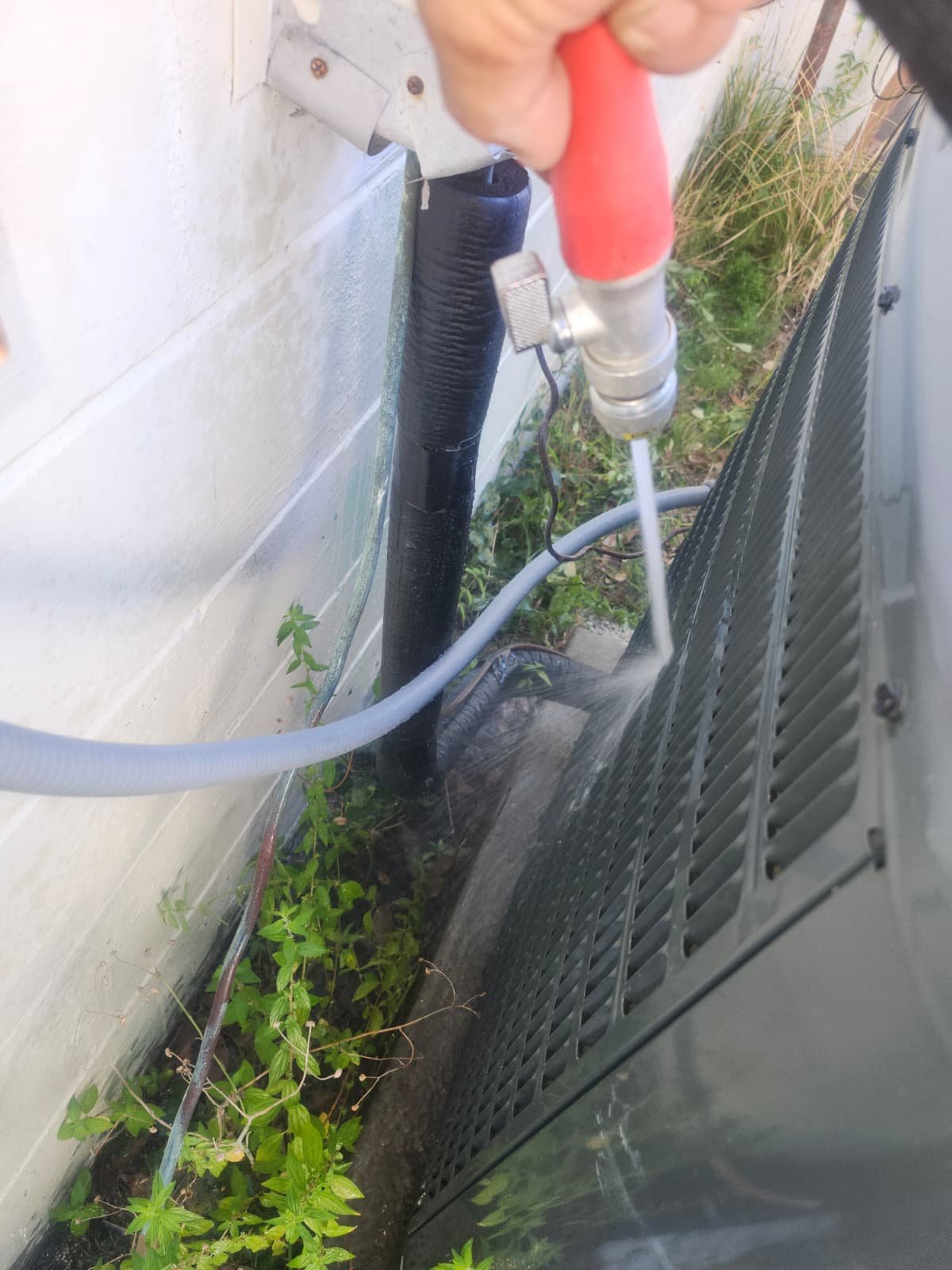 Side AC Unit Cleaning - Tampa, FL 33611 Cleaning side of outdoor AC unit with hose in Tampa, FL 33611.