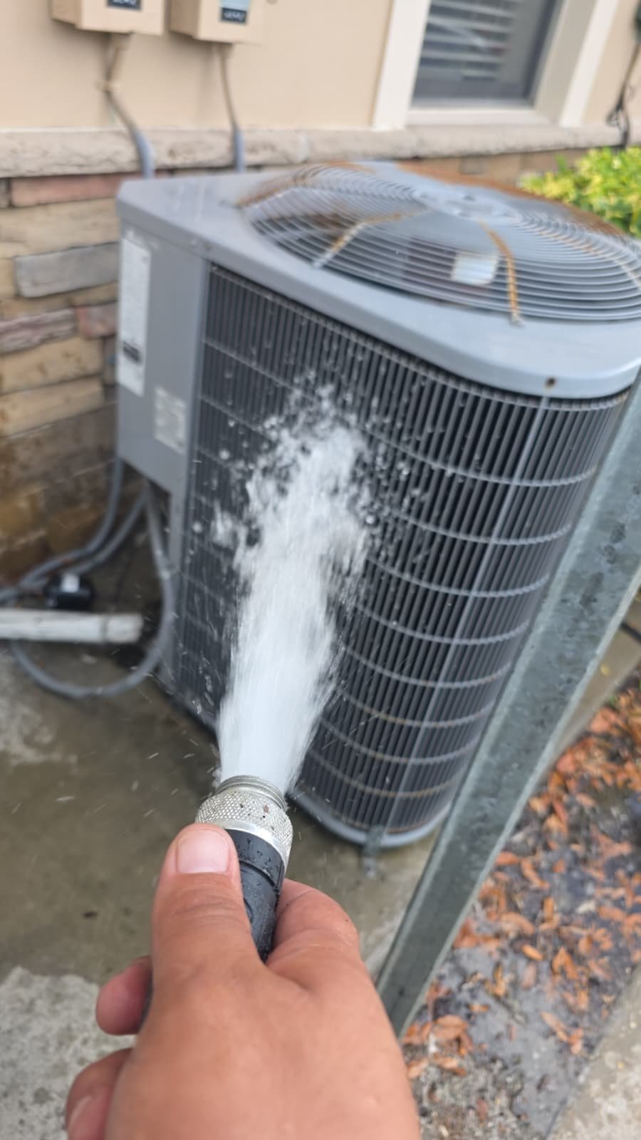 AC Unit Cleaning in New Port Richey, FL 34655 Outdoor AC unit being cleaned with a hose in New Port Richey, FL 34655.