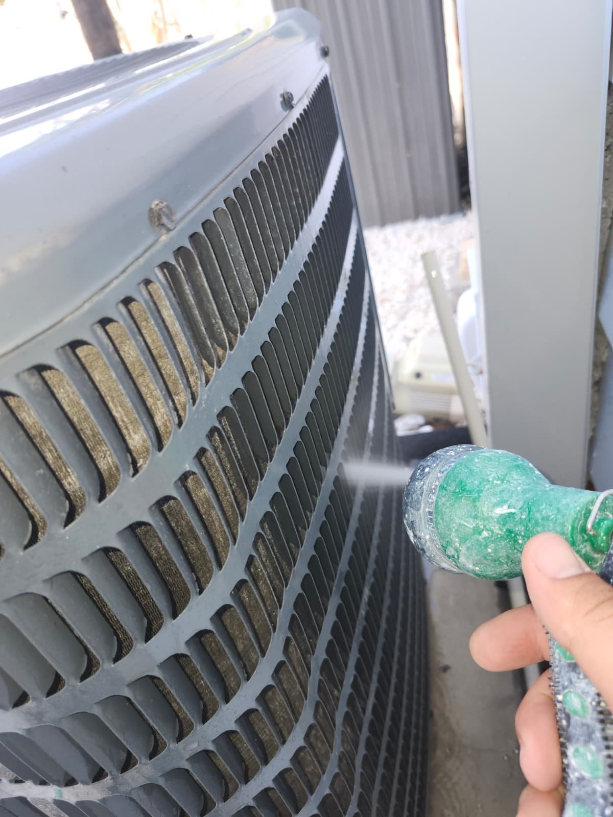 Cleaning outdoor AC unit with hose in St. Petersburg, FL 33703.
