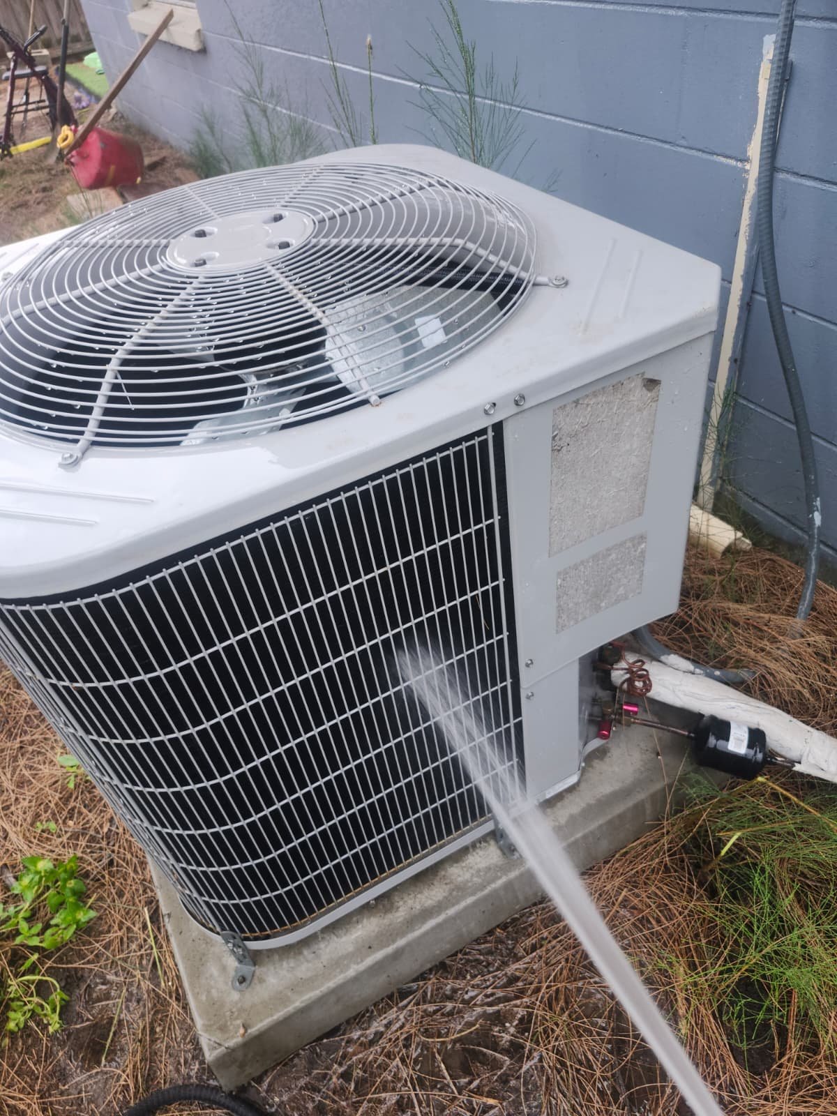 Outdoor AC unit being cleaned with a hose during Visit #3 in Tampa, FL 33619.