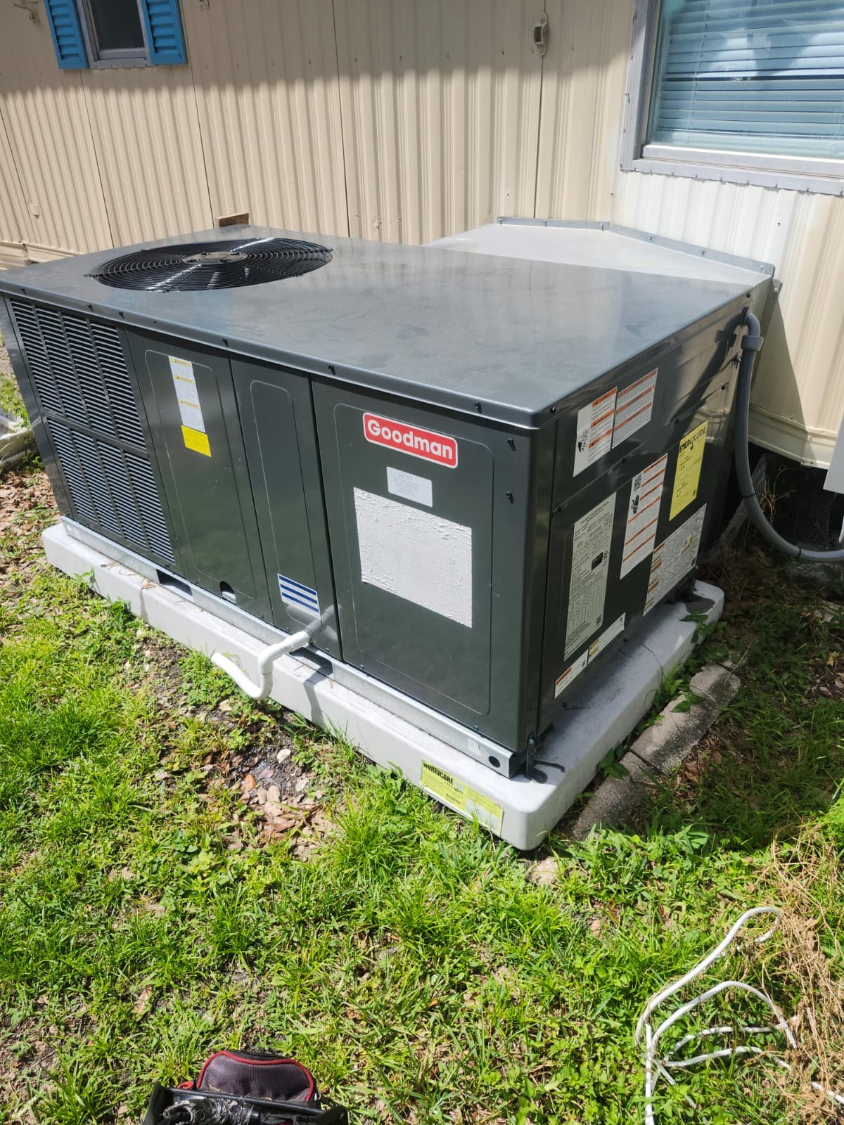 Goodman AC unit installed on concrete pad in Odessa, FL 33556. Durable and efficient.
