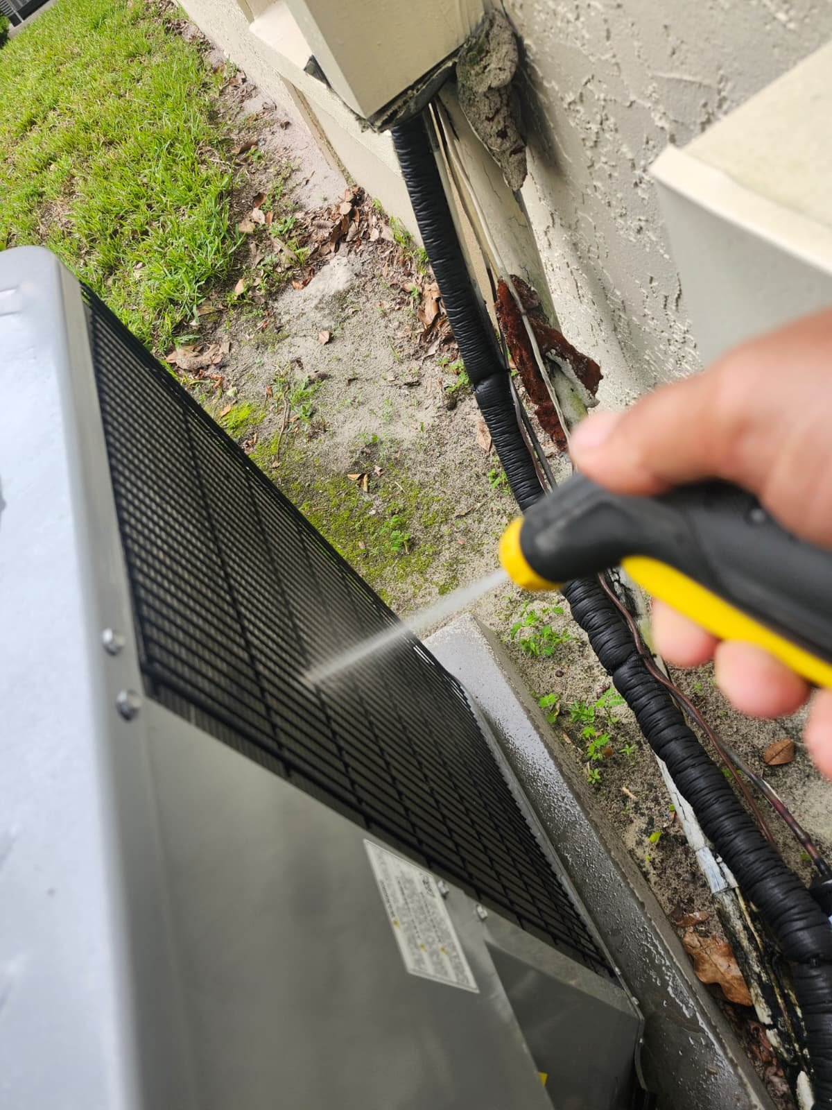 AC Unit Hose Cleaning in Tarpon Springs, FL 34688 Person cleaning outdoor AC unit with hose in Tarpon Springs, FL 34688. Effective HVAC maintenance.