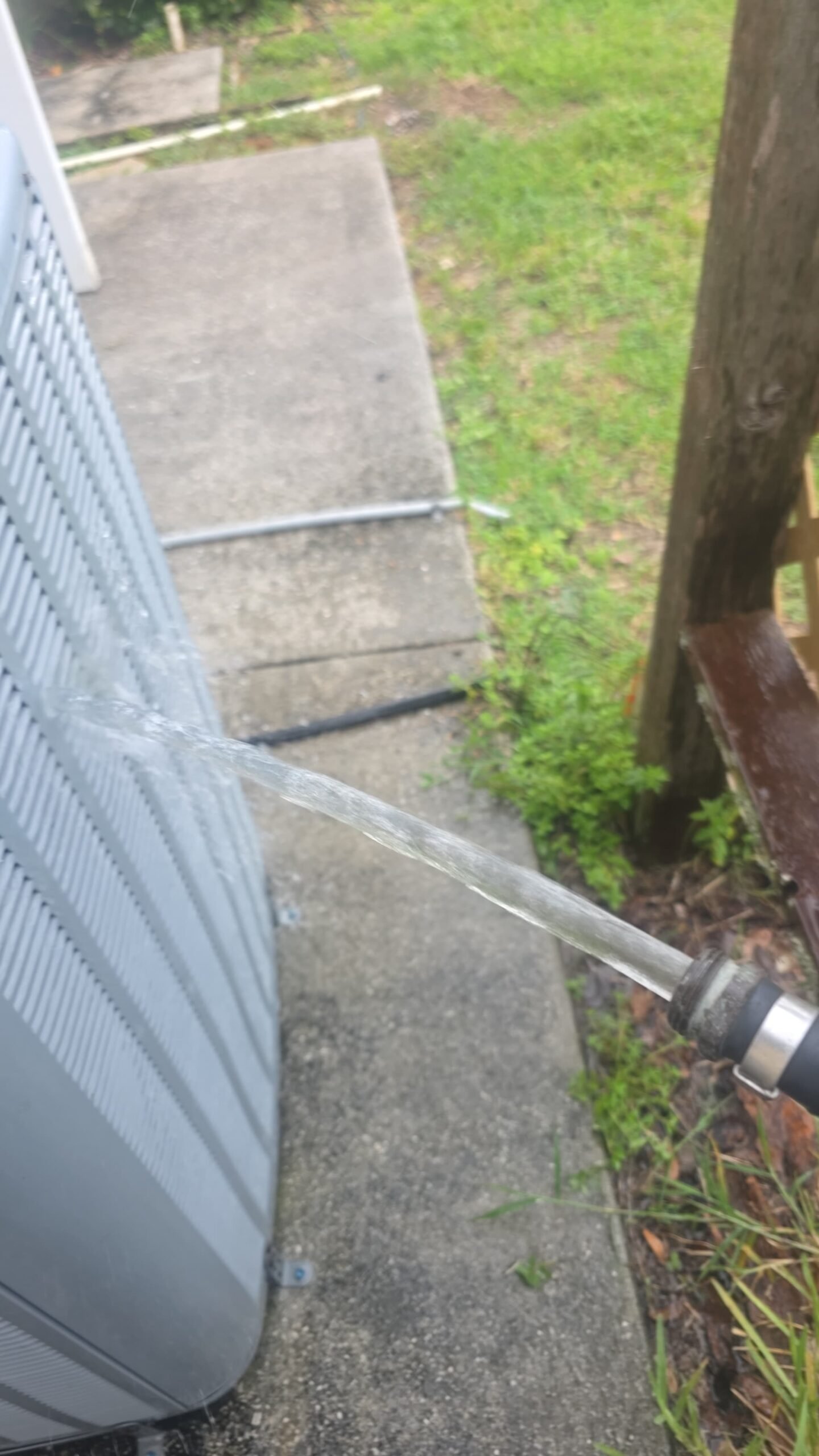 Water hose spraying outdoor AC unit, Elite Therapy Visit #7, Bradenton, FL 34202.