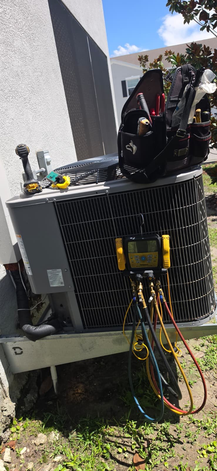 Outdoor AC unit with tools and gauges in Odessa, FL 33556. Professional maintenance service.