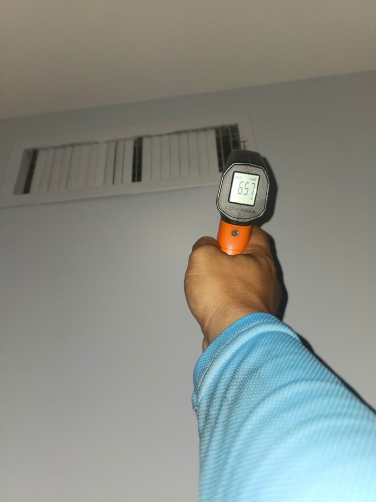 Checking supply air temperature at a vent with an infrared thermometer in Tampa, FL 33618.