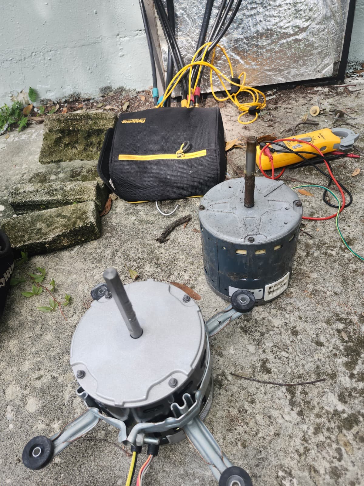 Two blower motors with tools and wires on the ground in Tampa, FL 33618. Equipment for replacement.