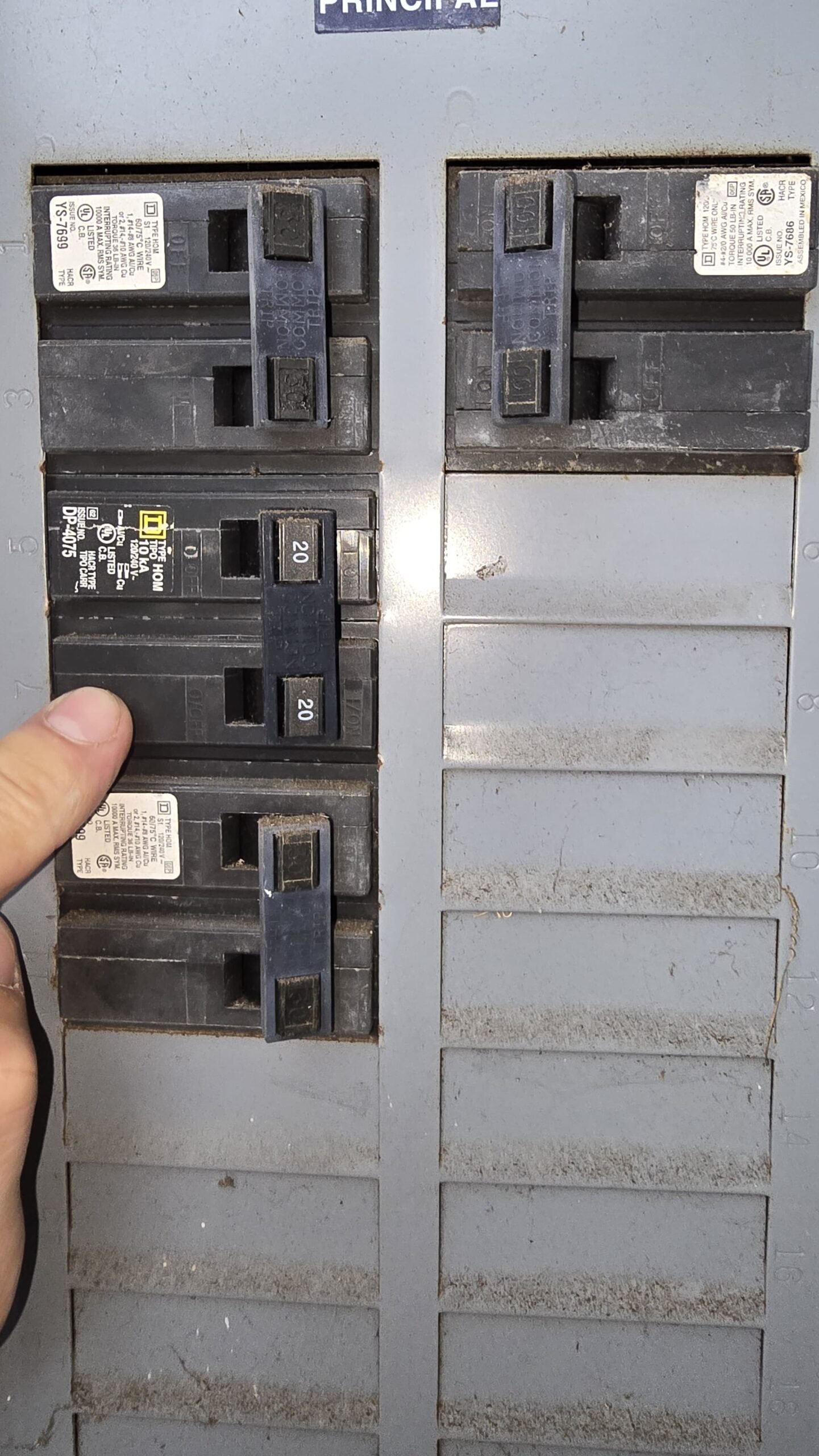 Finger pointing to switch in circuit breaker panel, Tampa, FL 33613.