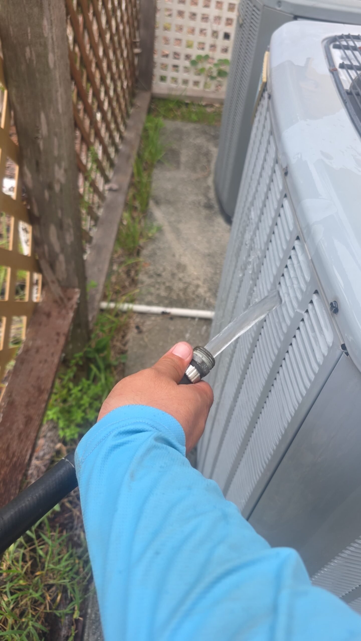 Cleaning outdoor AC unit with hose during Elite Therapy Plan in Bradenton, FL 34202.