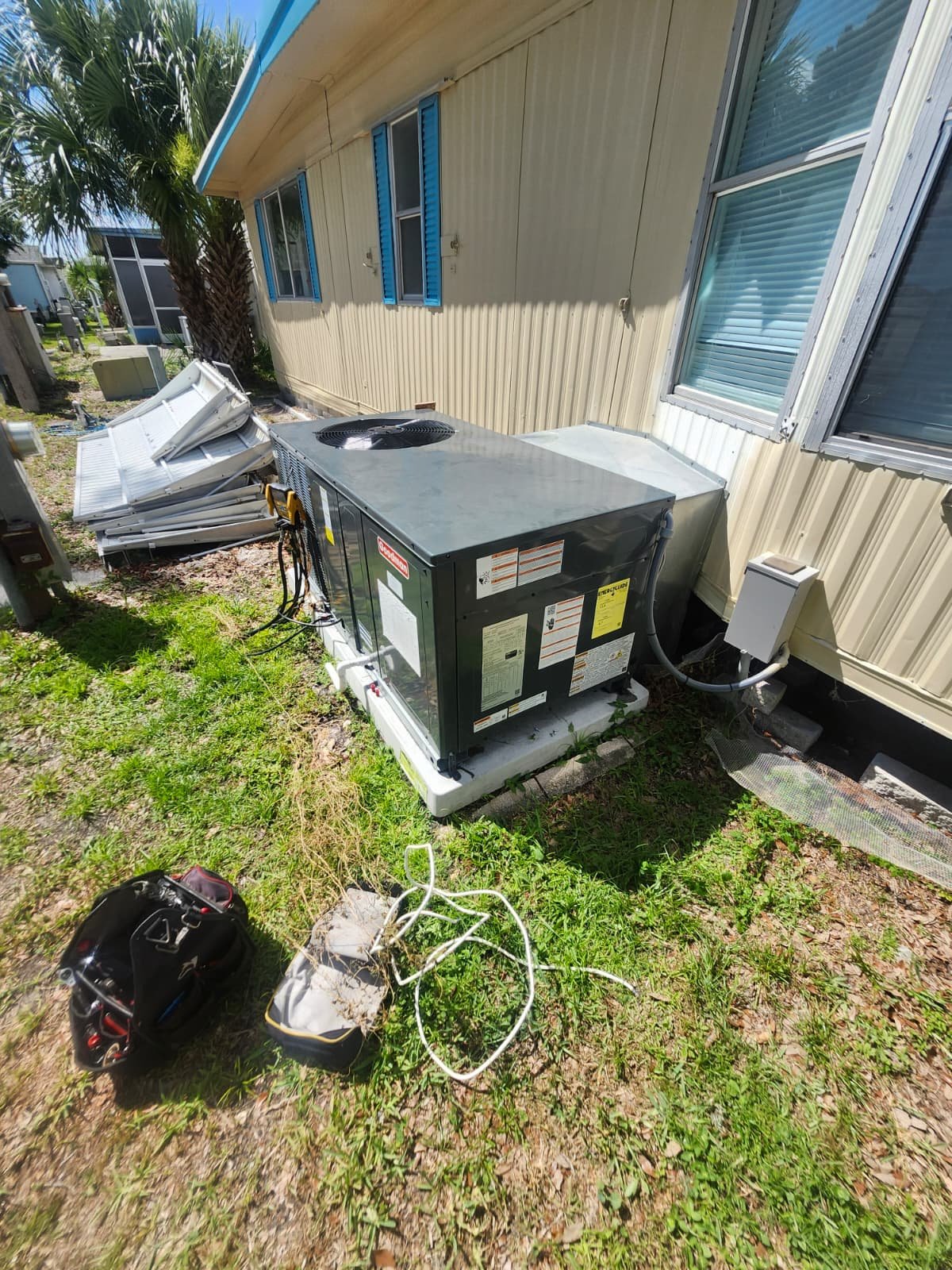 Installed AC unit beside mobile home with tools nearby in Odessa, FL 33556. Ready for use.