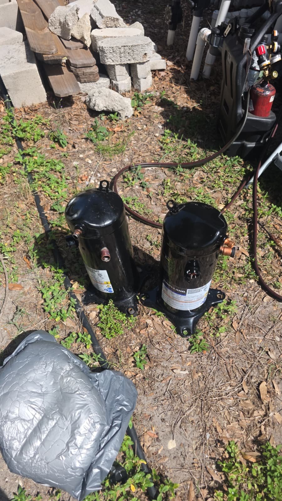 Two compressors placed on the ground during replacement in Riverview, FL 33579. In-progress AC service.