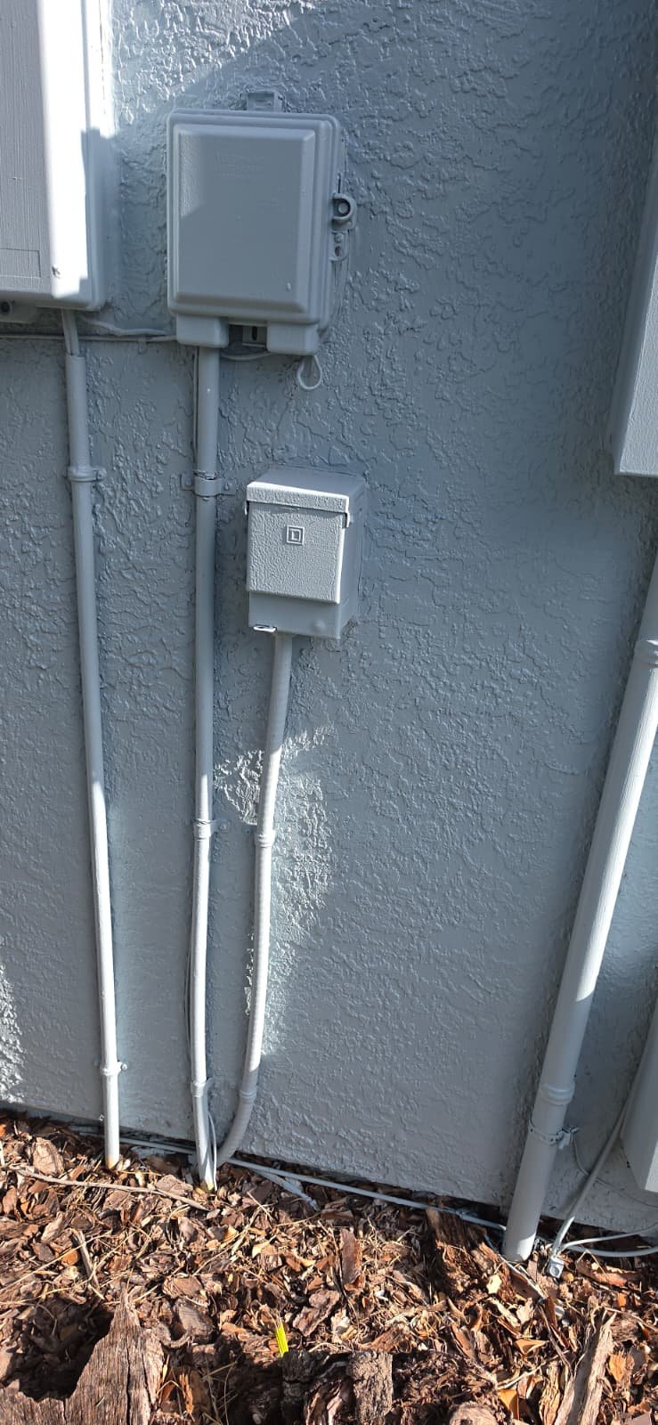 Exterior electrical boxes and conduit on house wall in Tampa, FL 33624.
