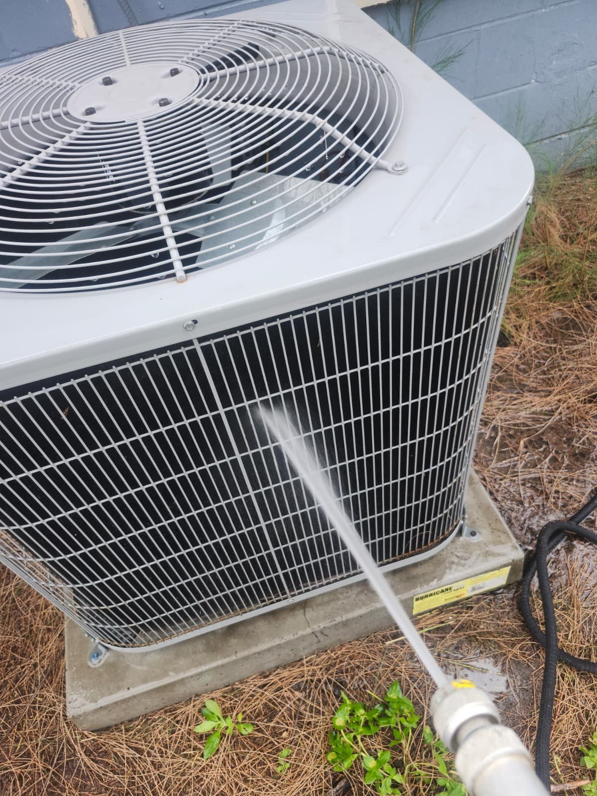 Outdoor AC unit being cleaned with a hose during Visit #3 in Tampa, FL 33619.