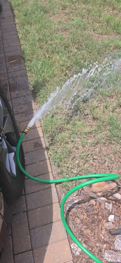 Hose spraying water onto grass in Wimauma, FL 33598