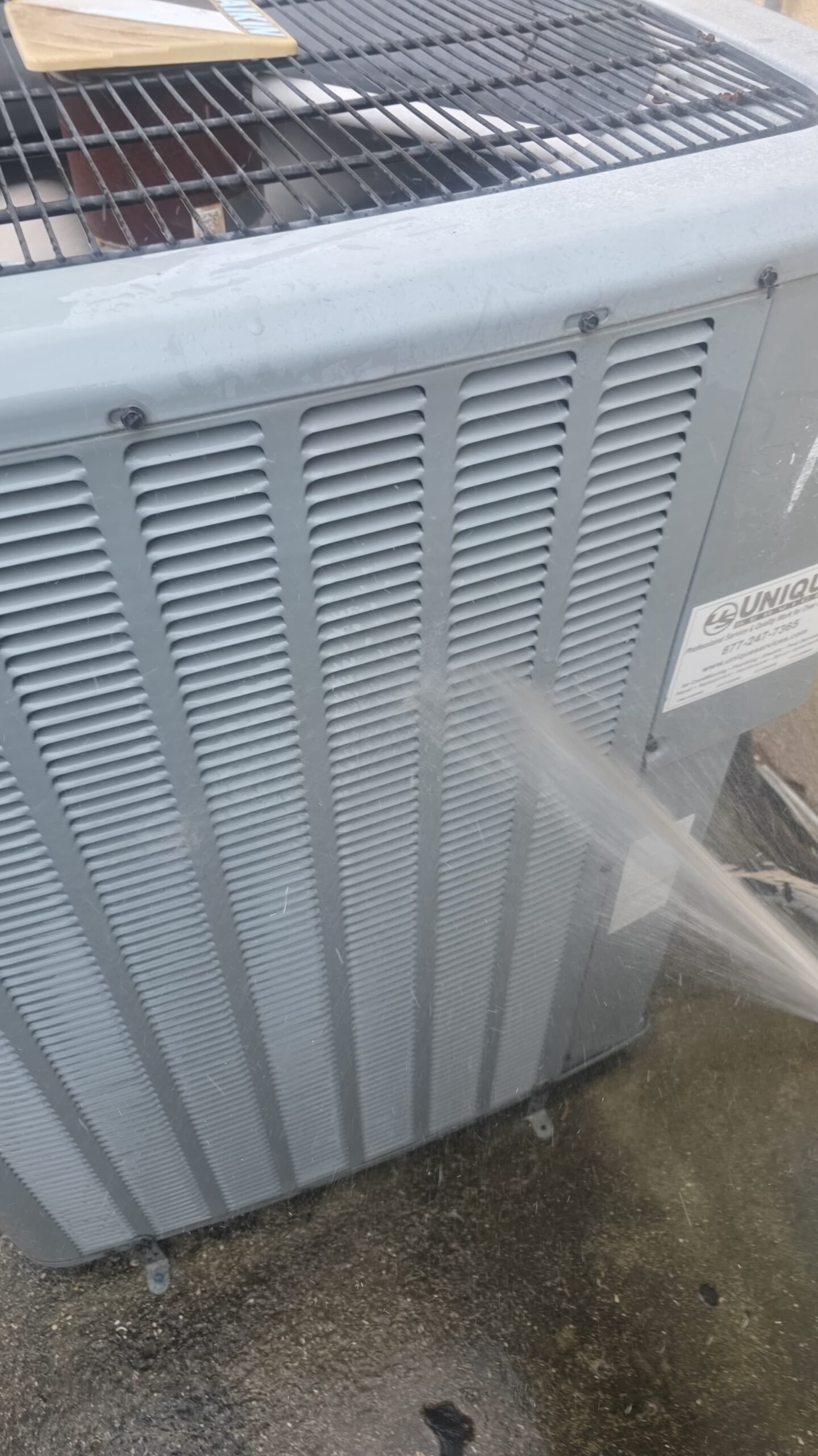 HVAC unit being cleaned with water hose during Elite Therapy Plan in Bradenton, FL 34202.