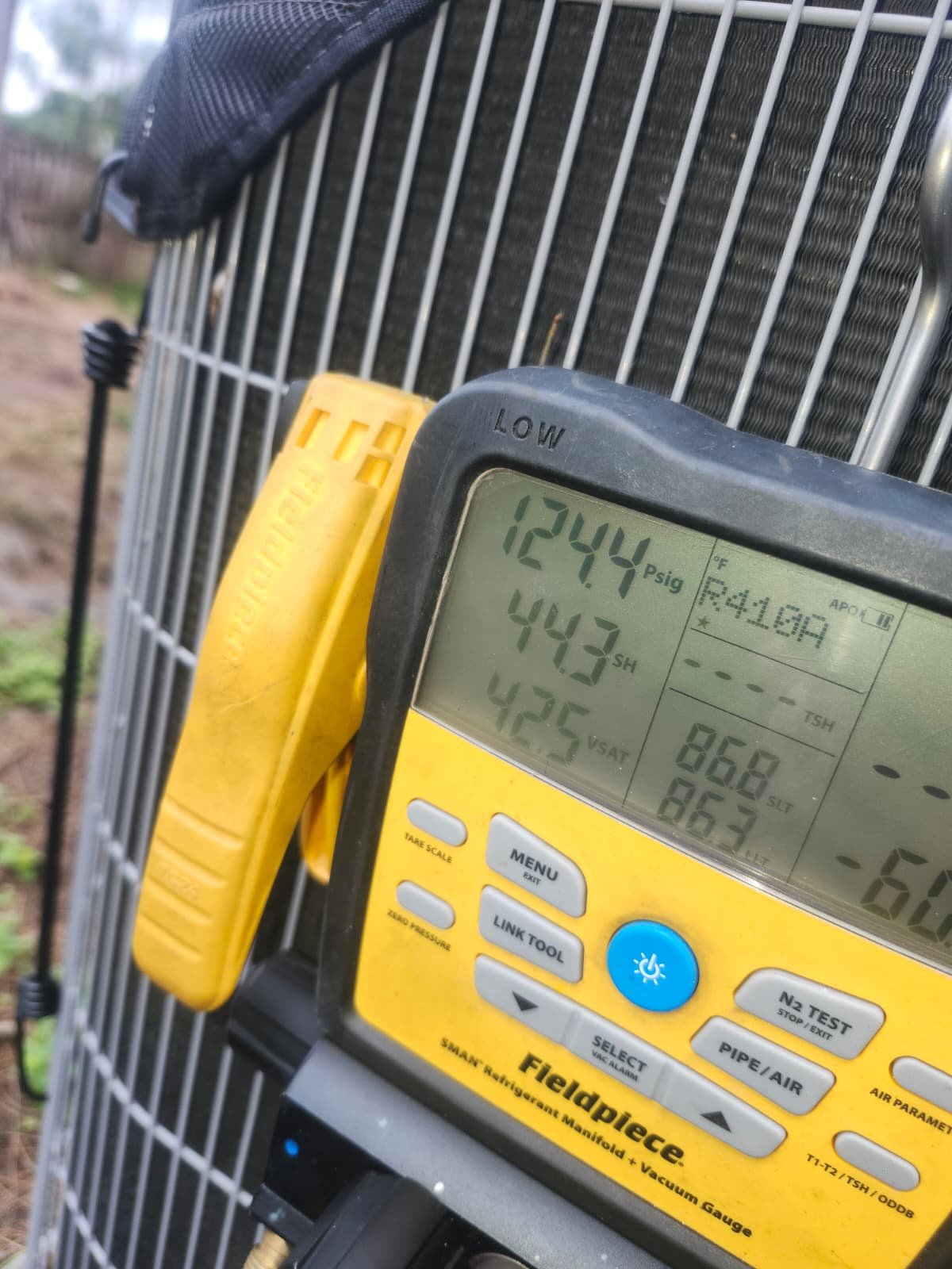Close-up of HVAC unit with diagnostic tool showing readings in Tampa, FL 33619.