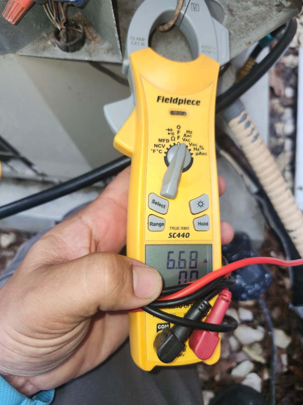 Technician using multimeter on HVAC unit in Tampa, FL 33618.