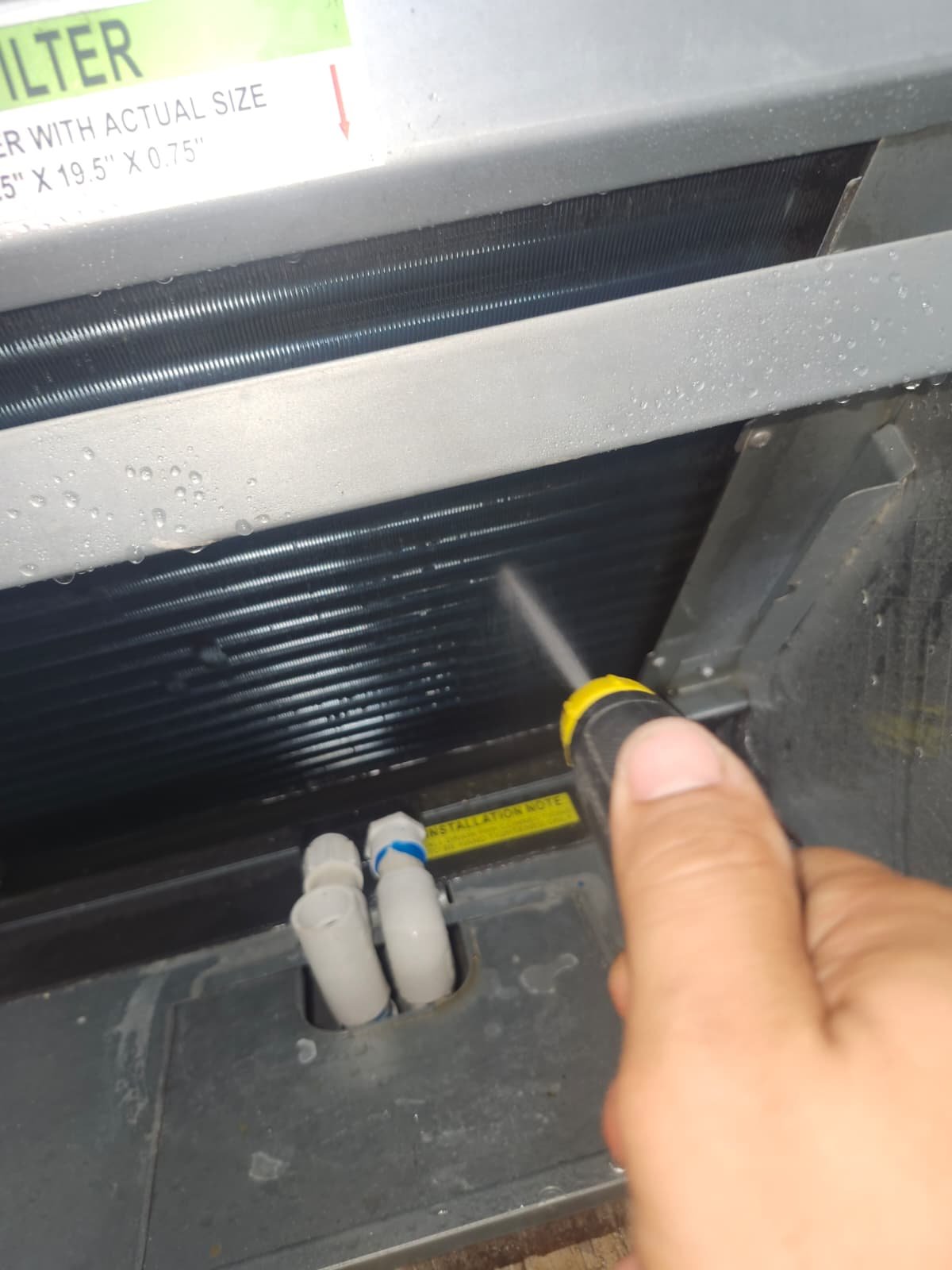 HVAC Filter Area Cleaning in Tarpon Springs, FL 34688 Spraying water inside HVAC unit near filter area in Tarpon Springs, FL 34688. Detailed HVAC maintenance.
