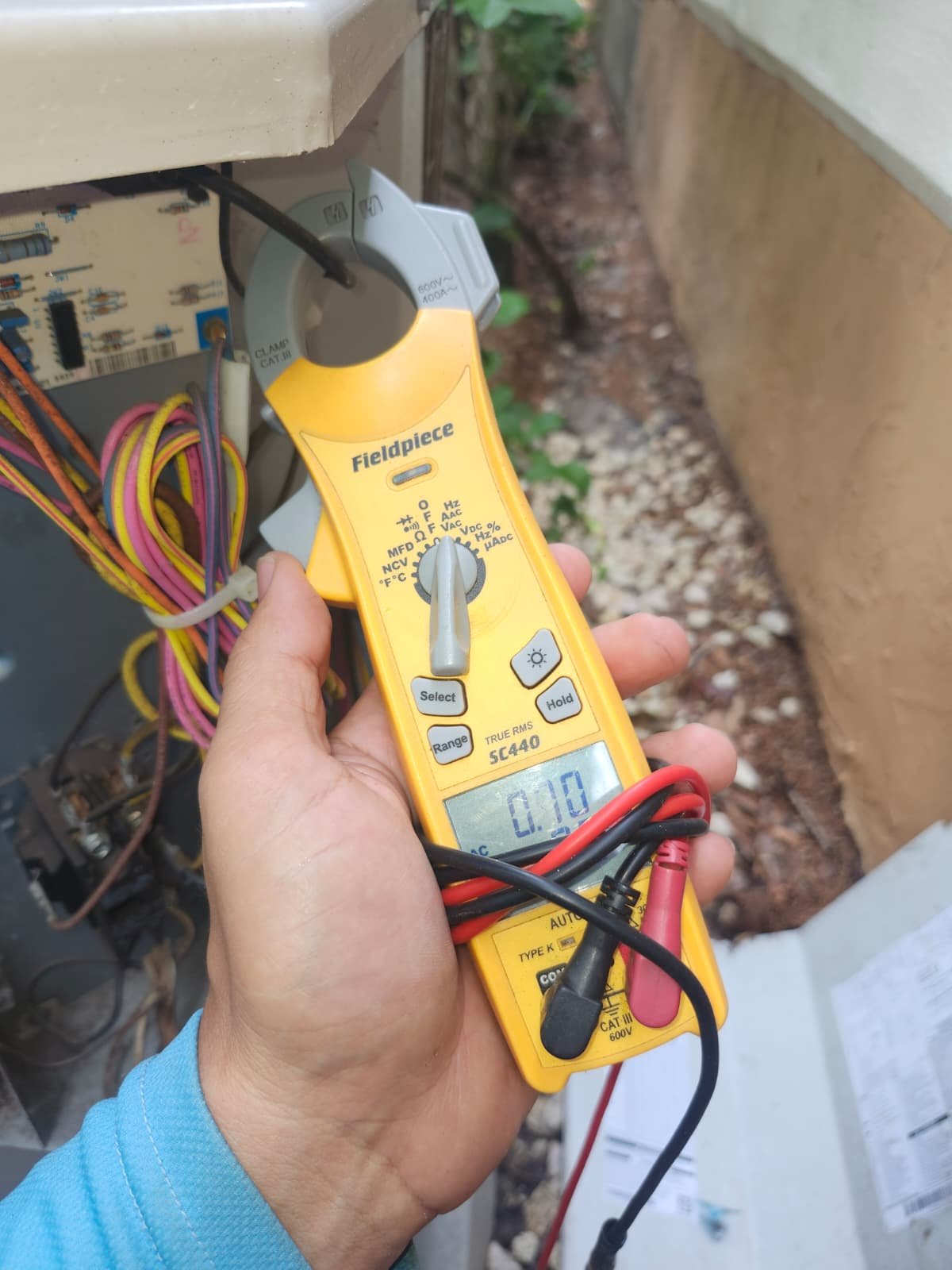 Technician using multimeter on HVAC unit in Tampa, FL 33618.