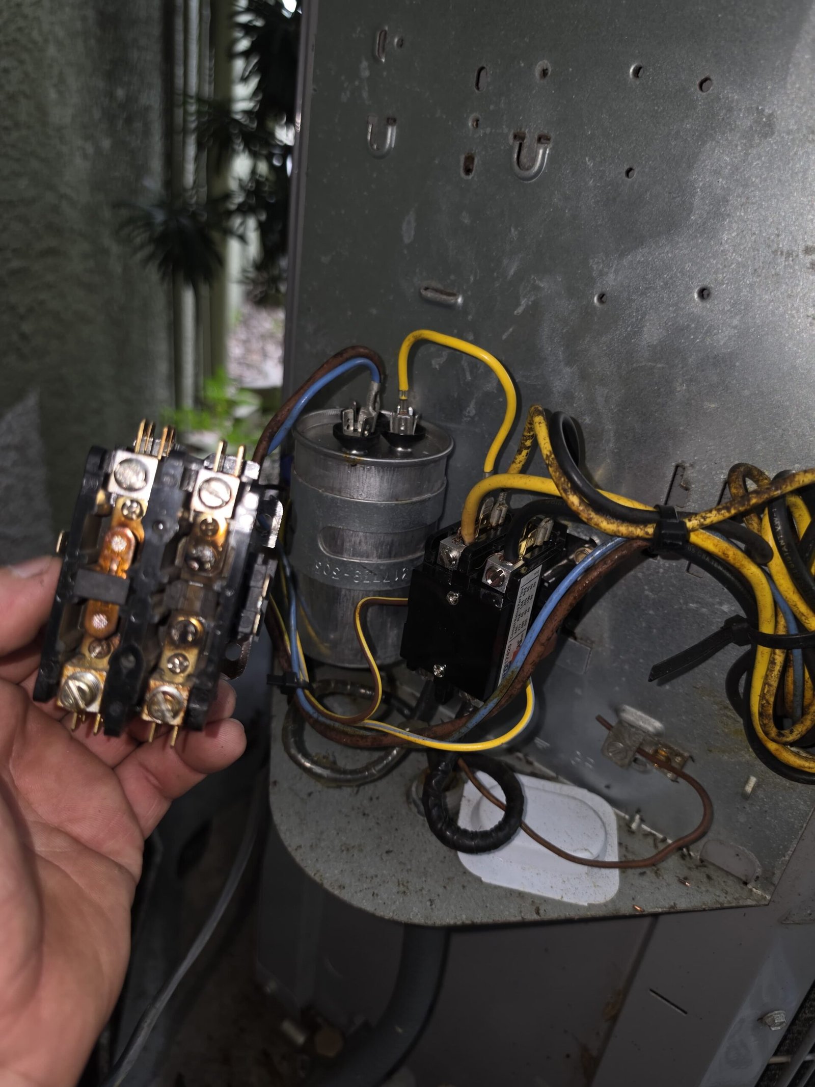 HVAC Repair In-Progress - Tampa, FL 33625 Technician holding a component inside an HVAC unit in Tampa, FL 33625. In-progress repair work.