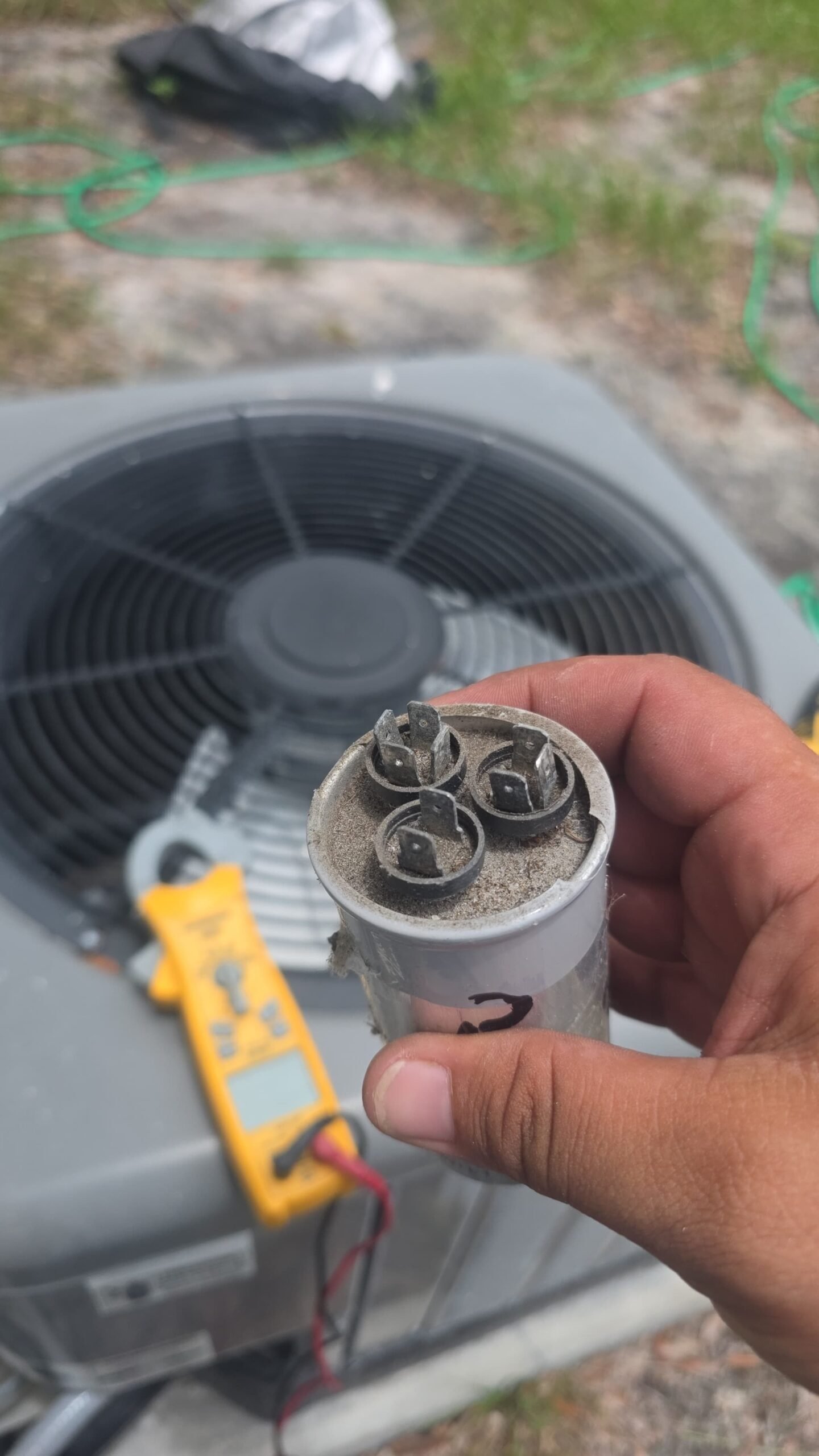Technician with dusty capacitor near HVAC unit, Largo, FL 33774.