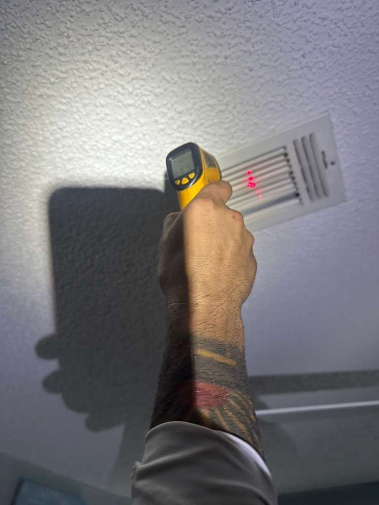 Close-up of technician using infrared thermometer on ceiling vent in Plant City, FL 33565.