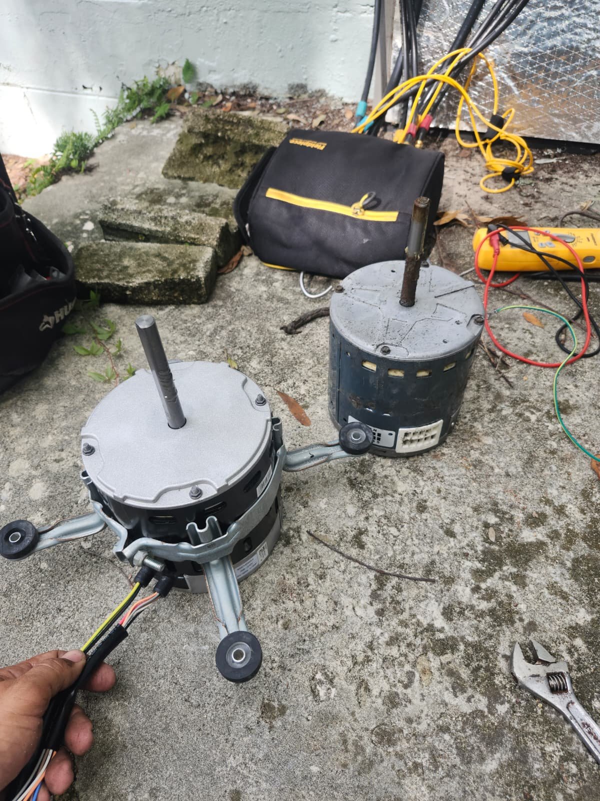 Old and new blower motors on the ground with tools in Tampa, FL 33618. HVAC replacement process.