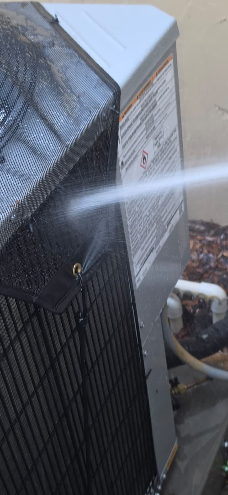 Outdoor AC unit being cleaned with a water spray in Lutz, FL 33559.