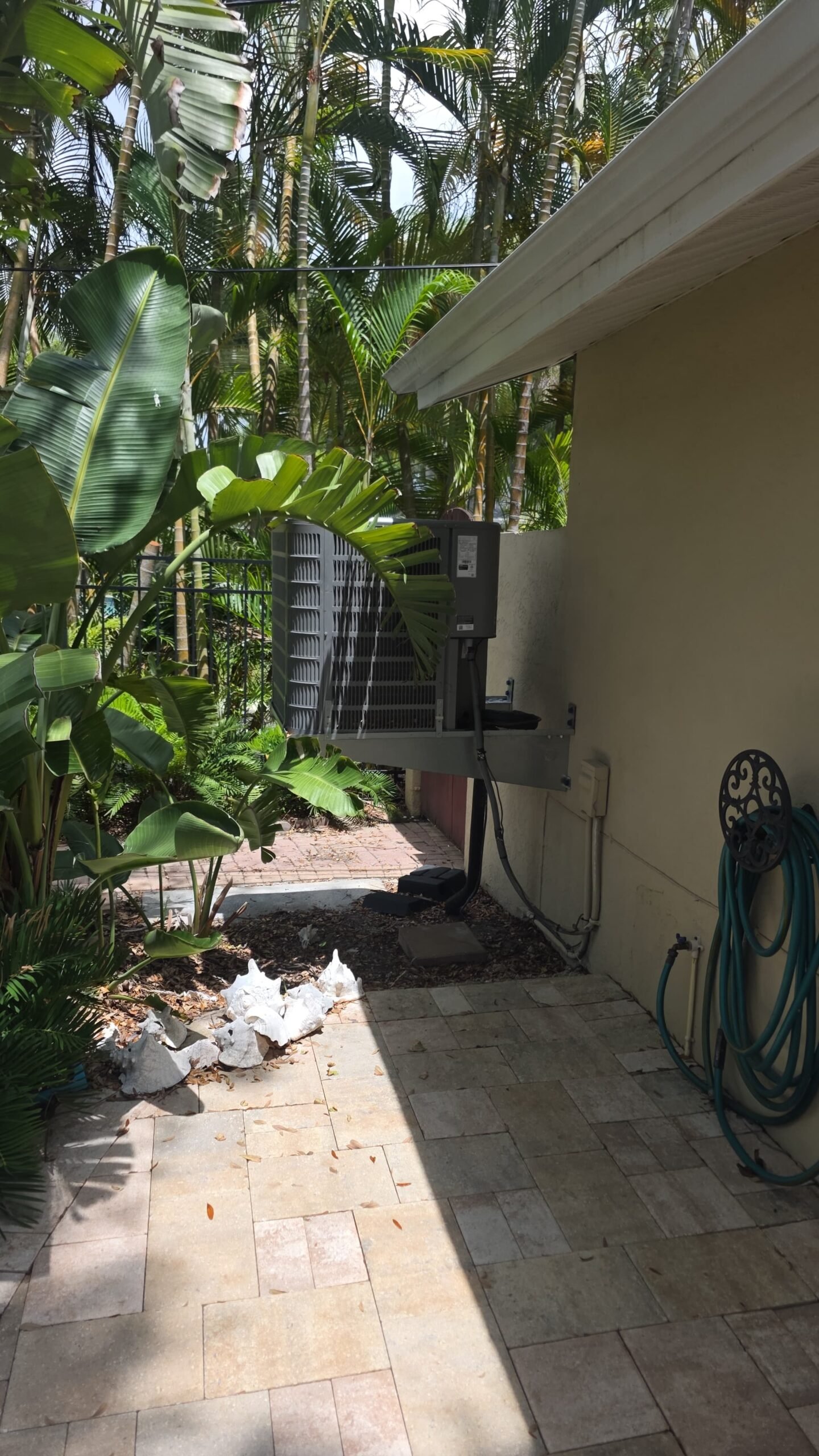 Outdoor AC unit installed beside house with foliage, Tampa, FL 33606.