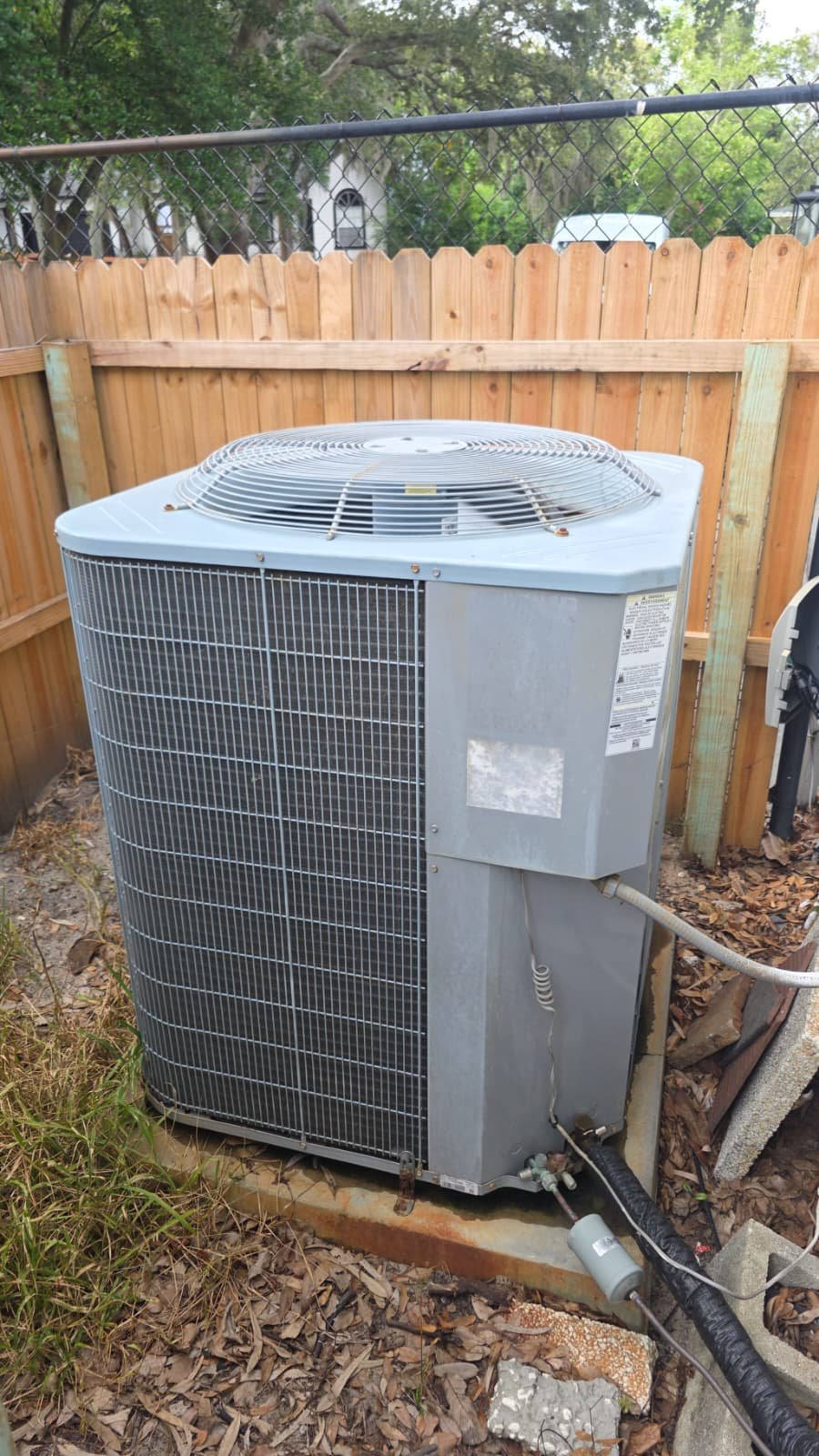 Outdoor Carrier AC unit installed beside wooden fence during Premium Therapy Plan in Tarpon Springs, FL 34689.