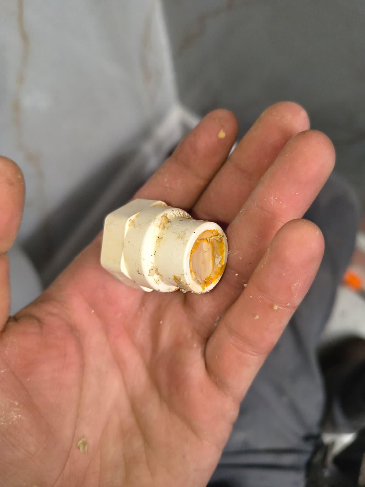 Hand holding plumbing fitting with residue, Tampa, FL 33603.