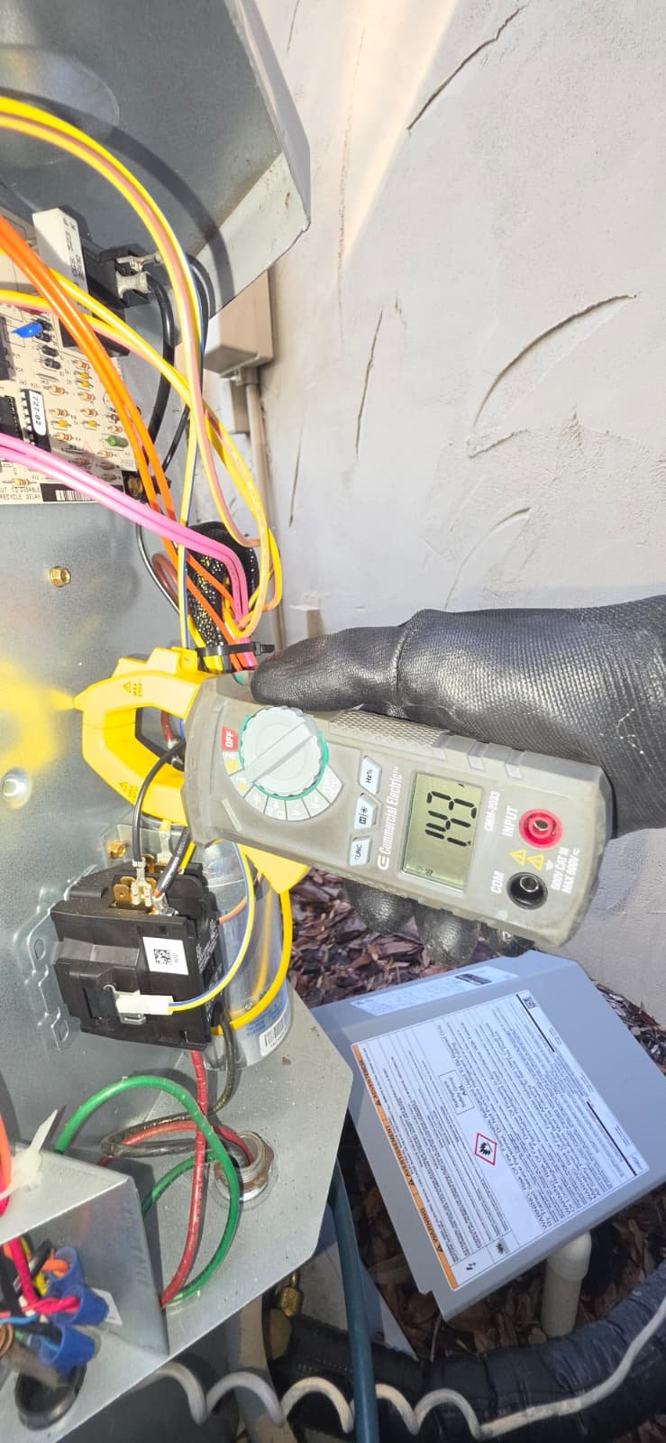 Technician using multimeter on outdoor unit in Lutz, FL 33559.