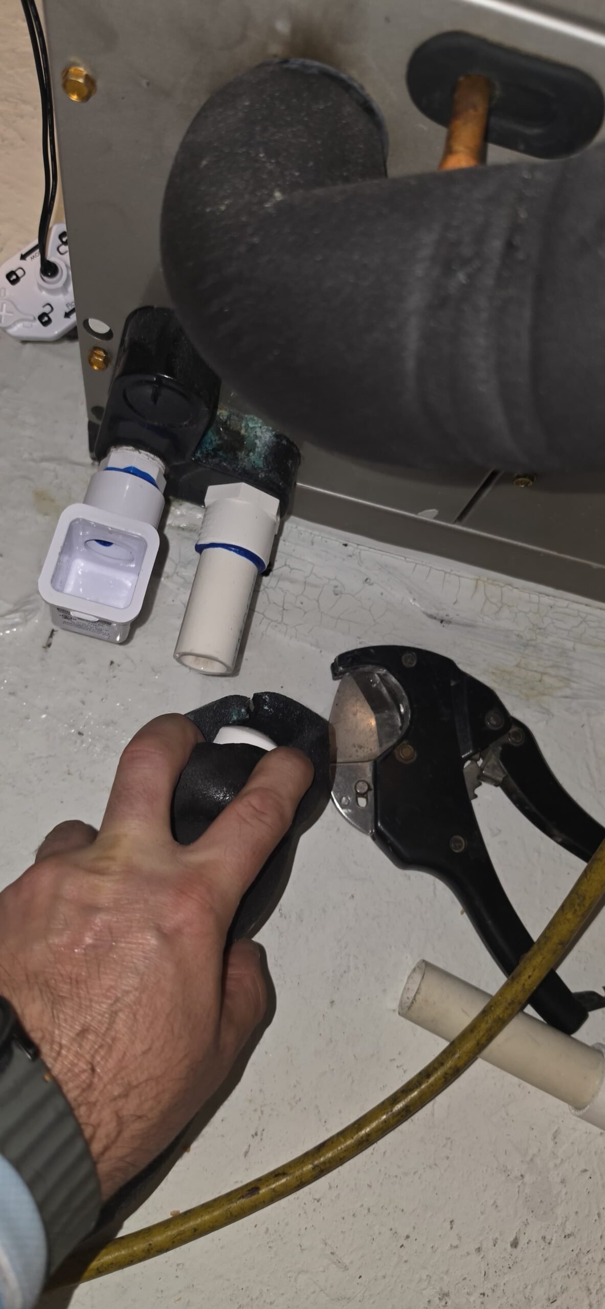 Tool Use Near Drain Line - Spring Hill, FL 34609 Hand holding tool near drain line connection in Spring Hill, FL 34609.