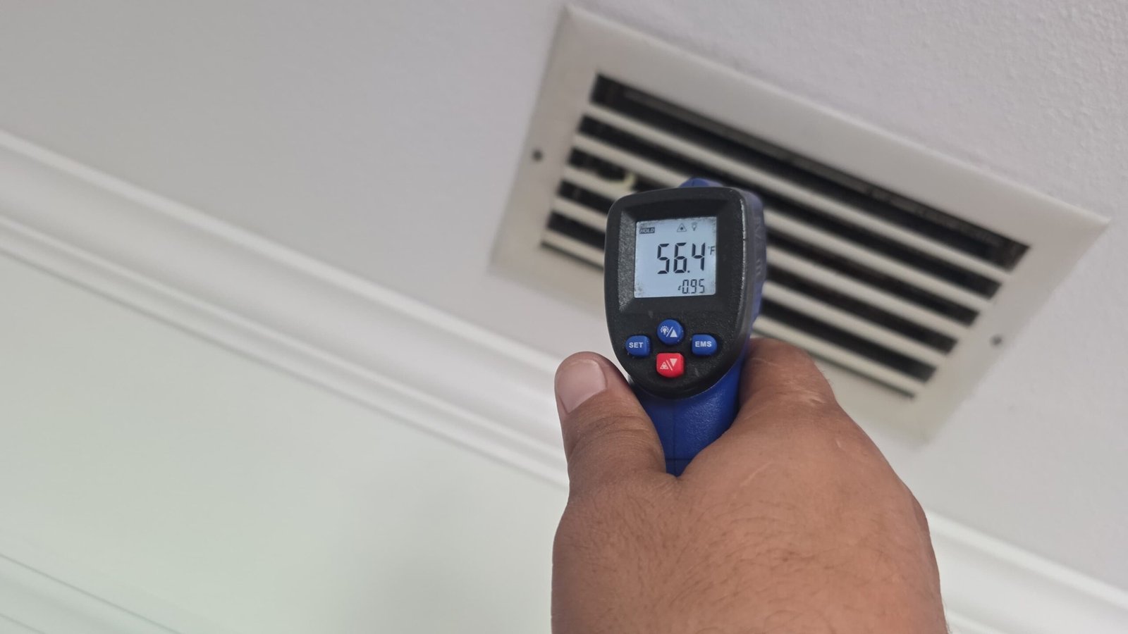 Infrared thermometer reading vent temperature for HVAC service in Largo, FL 33771.