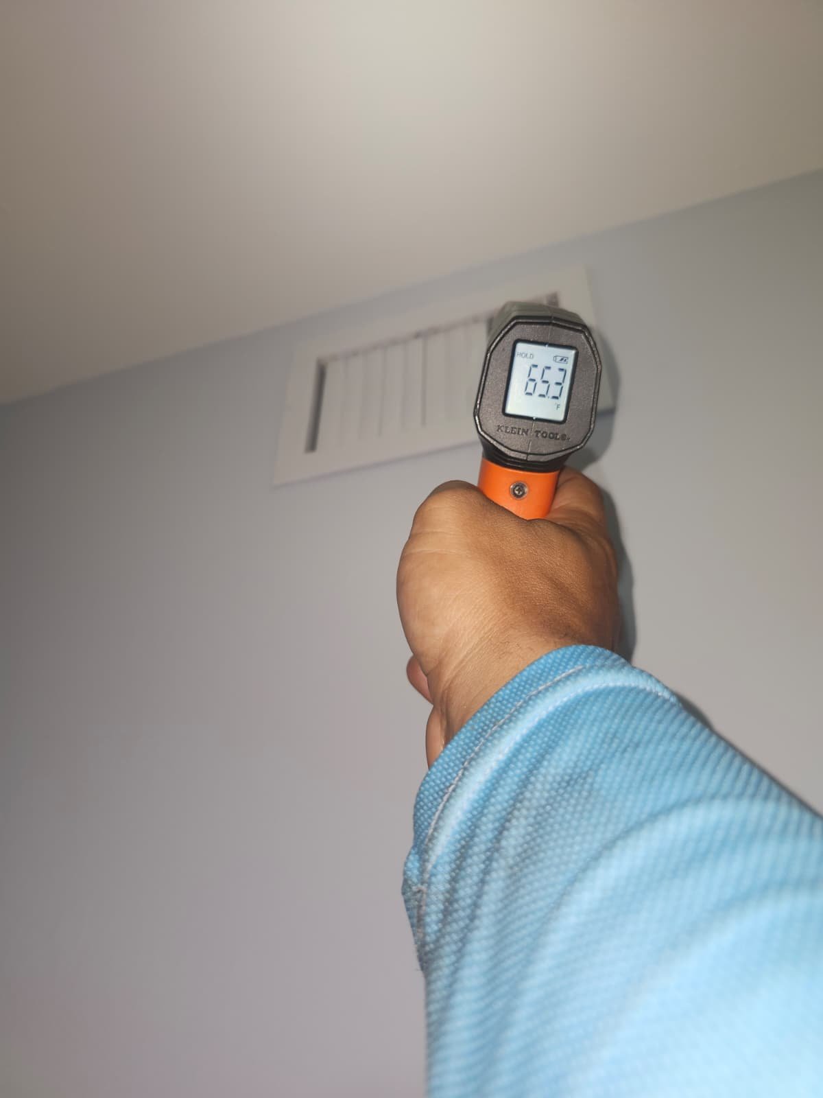 Person measuring air temperature at a vent with a thermometer in Tampa, FL 33618. HVAC service.