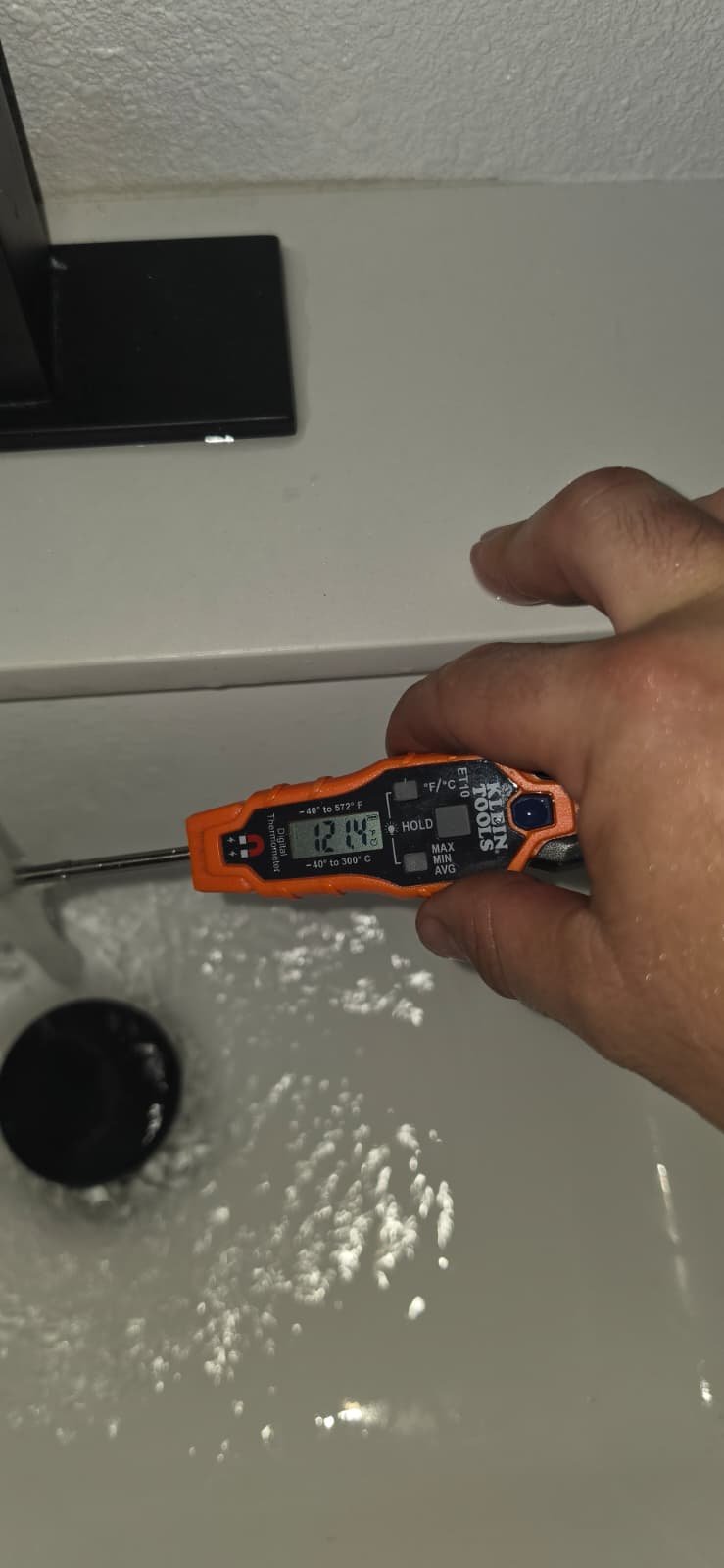 Water Temperature Check - Tampa, FL 33624 Hand with thermometer measuring water temperature in Tampa, FL 33624 sink.