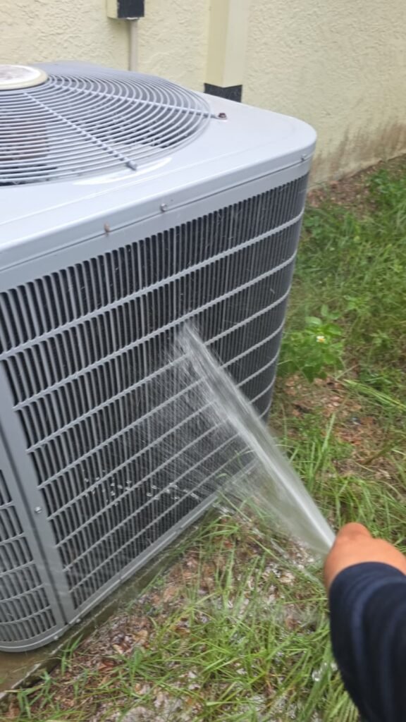 Rinsing an outdoor coil with a hose during a tune-up in Tampa, FL 33611.