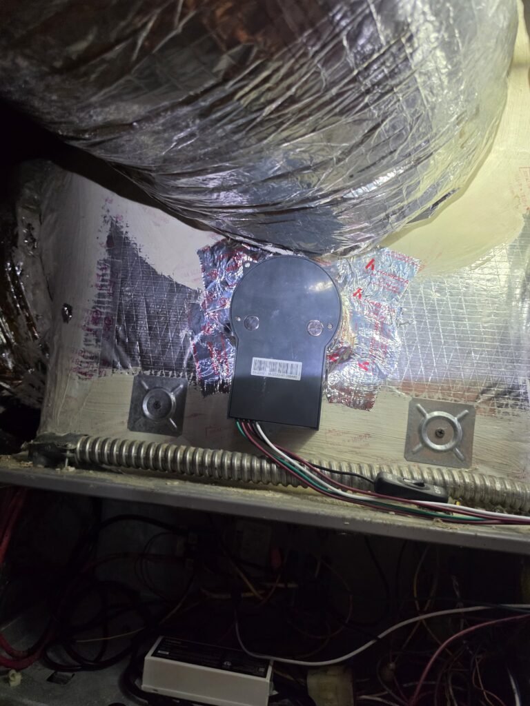 An air purifier mounted on the ductwork above an air handler in Tampa, FL 33615.