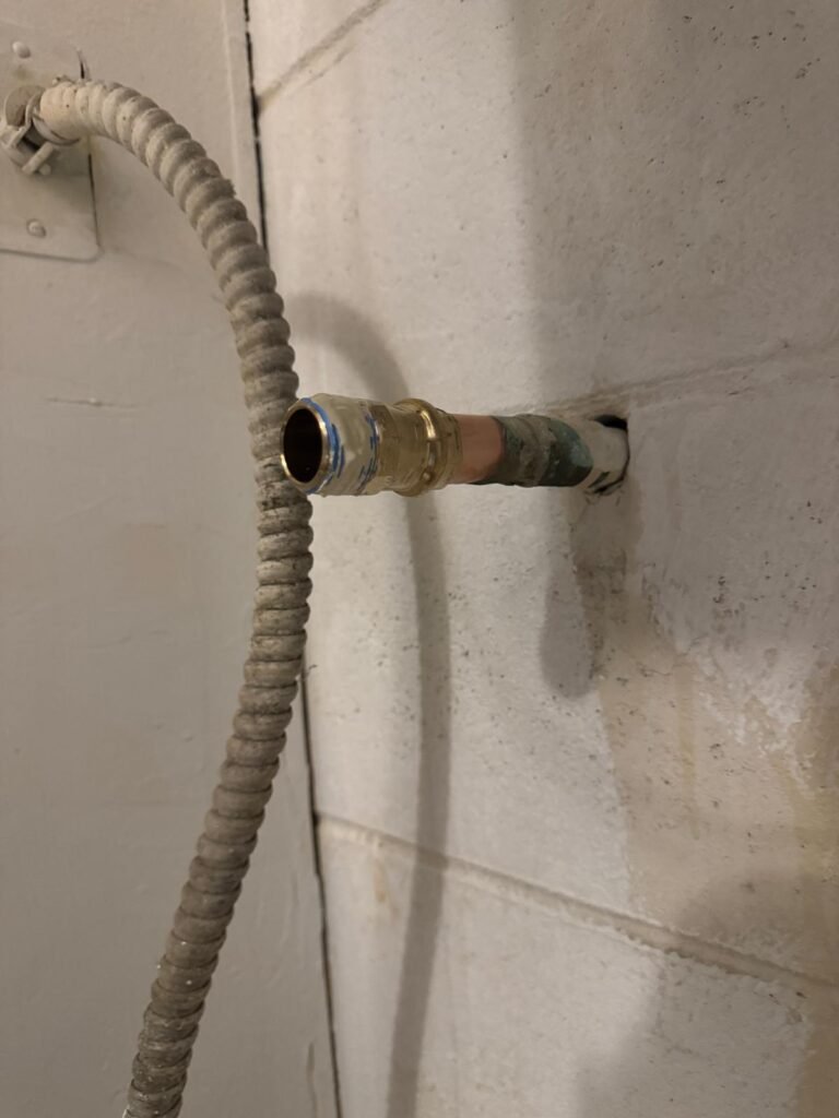 A copper supply line through a block wall with a brass fitting in Tampa, FL 33611.