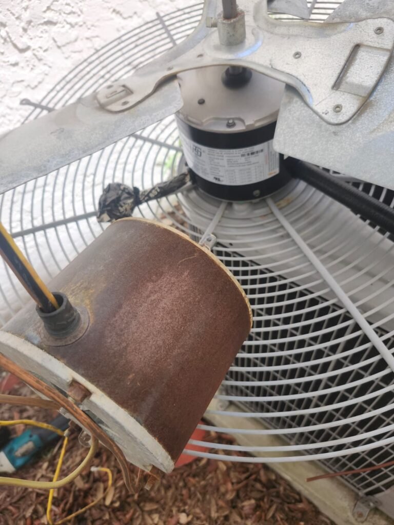 An old, rusted condenser fan motor next to the new motor mounted in the fan grille in Tampa, FL 33617.