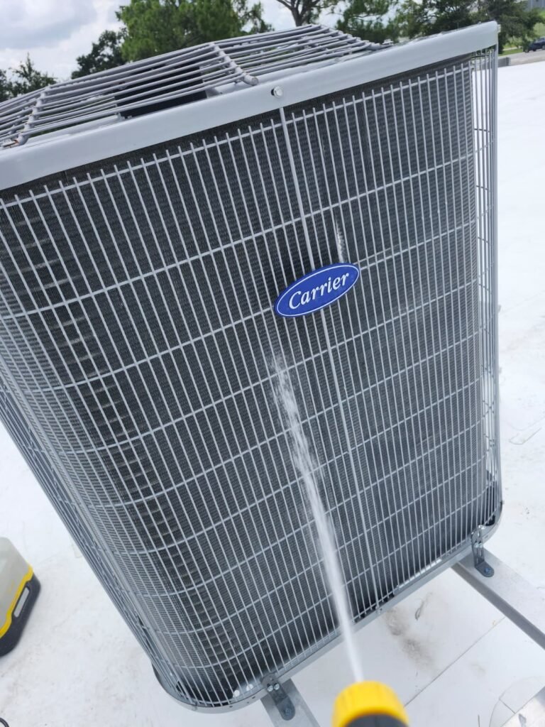 Rinsing an outdoor AC condenser coil with a hose during a tune-up in Tampa, FL 33634