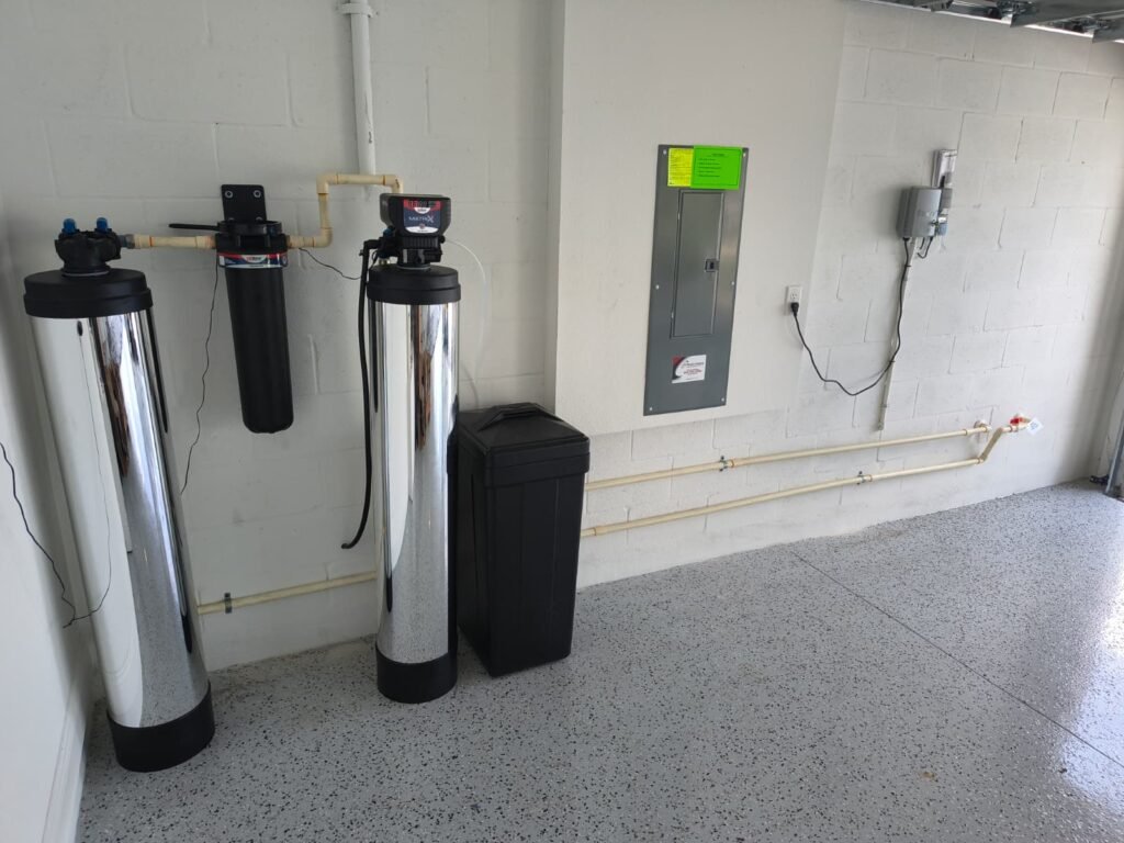 A water softener and brine tank next to whole-house filter tanks in a garage in San Antonio, FL 33576.