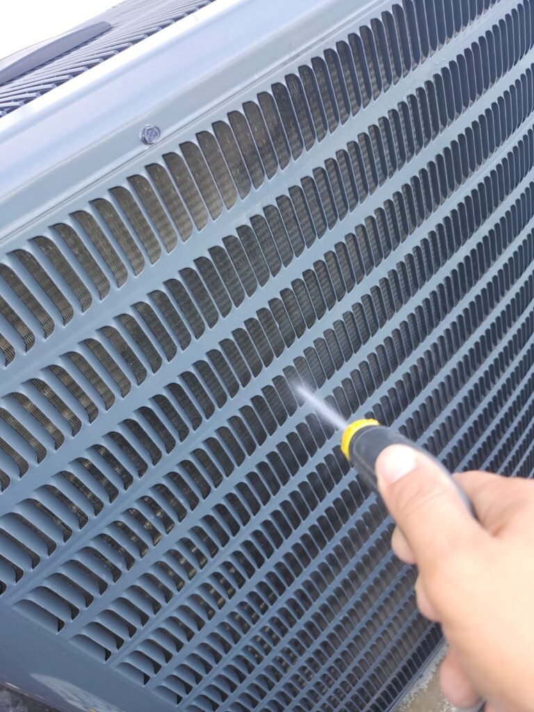 Rinsing the outdoor condenser coil during an AC tune-up in Tampa, FL 33634.