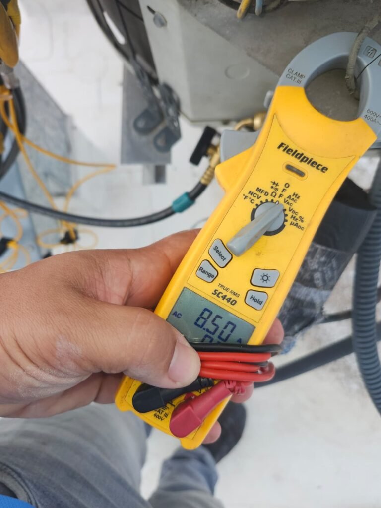 Reading amps with a clamp meter during HVAC service in Tampa, FL 33610.