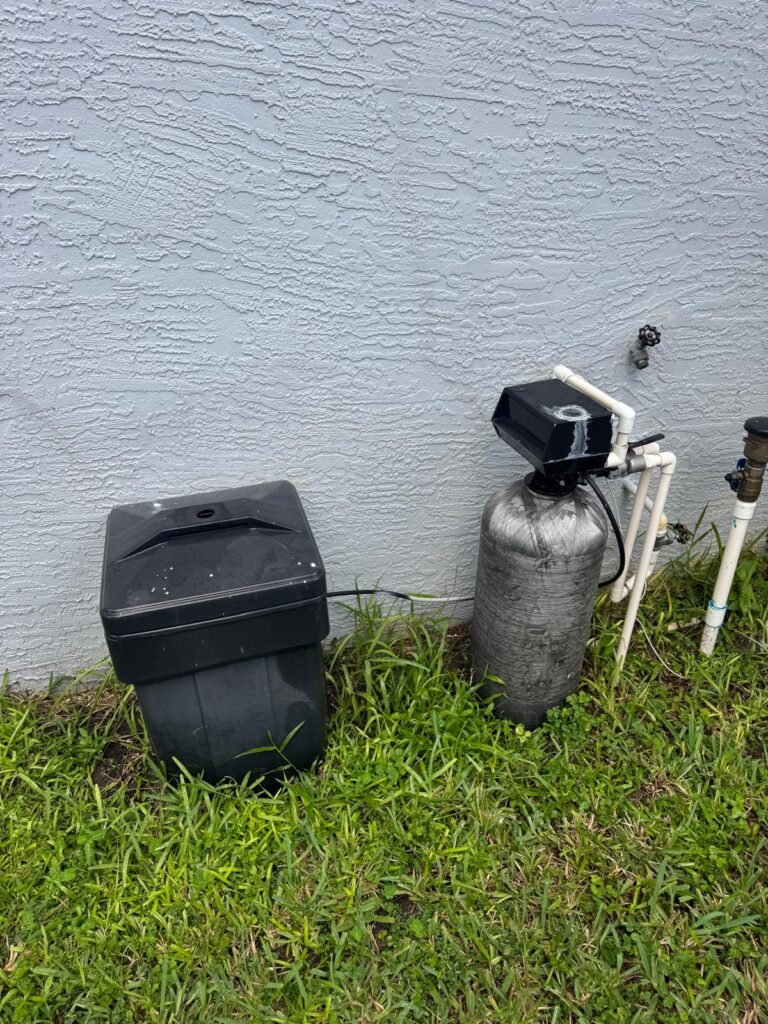 A water treatment tank and its brine tank installed against an outside wall in Riverview, FL 33579.