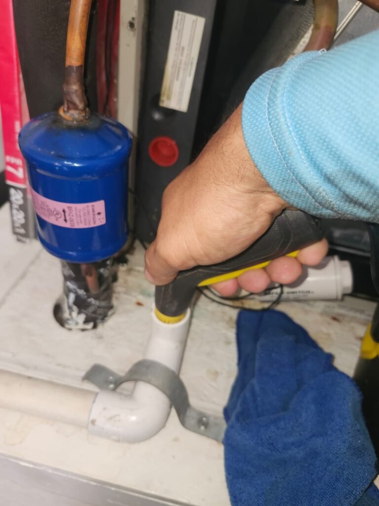 Technician clearing an AC condensate drain line in Tampa, FL 33610