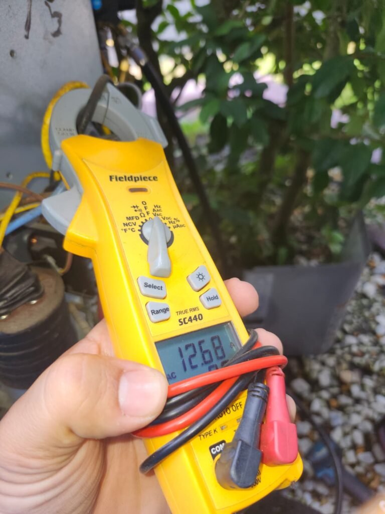 Checking electrical readings with a clamp meter during AC maintenance in Tampa, FL 33647.