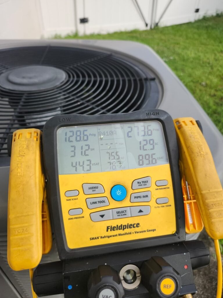 A digital manifold gauge reading refrigerant pressures on an AC unit in Tampa, FL 33625.
