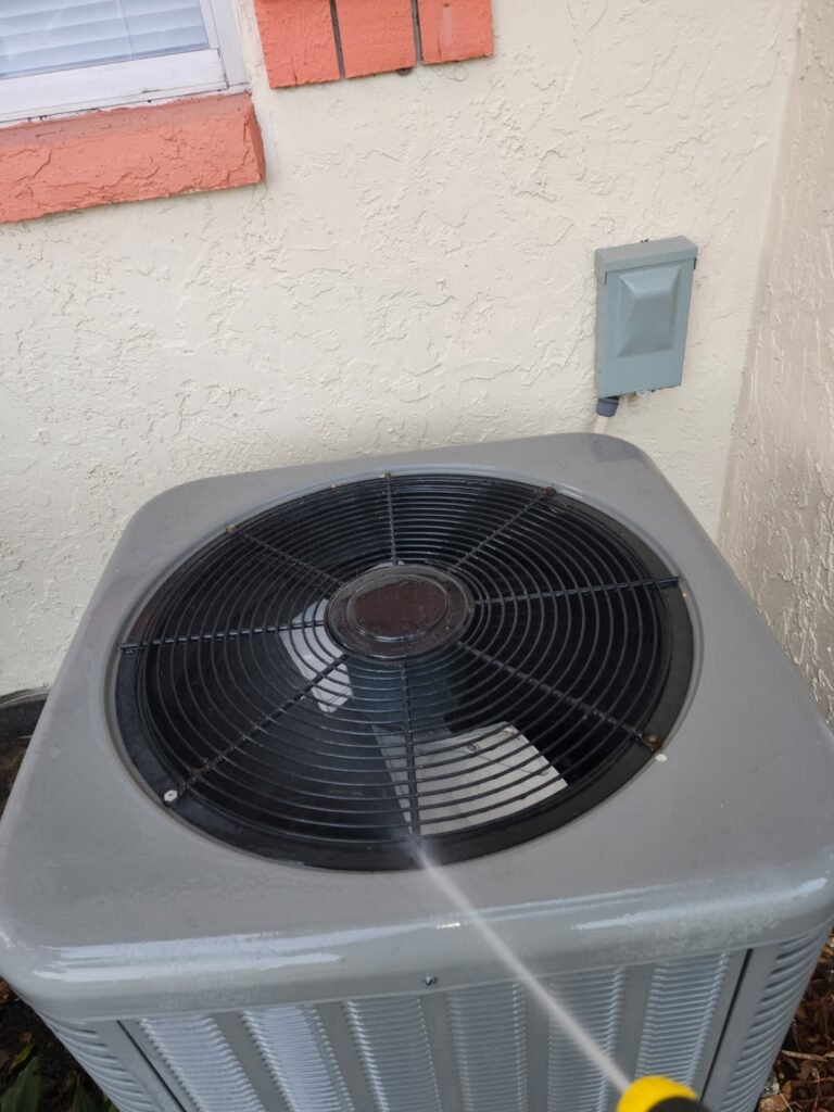 Rinsing an outdoor condenser with a hose during a tune-up in St. Petersburg, FL 33712.
