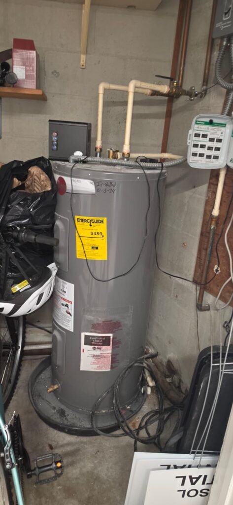 A new electric tank water heater installed in a garage in Tampa, FL 33606.
