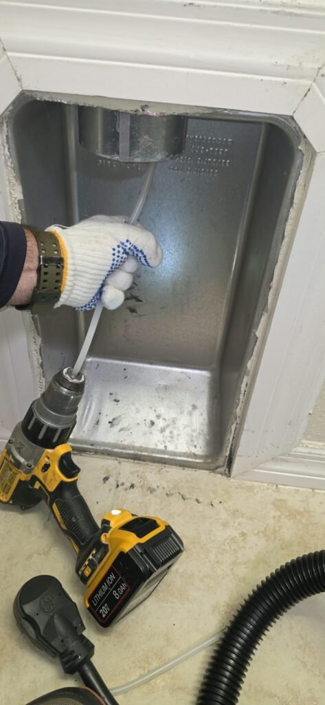 A drill-driven rotary brush cleaning the dryer vent box in a laundry wall in Tampa, FL 33647.